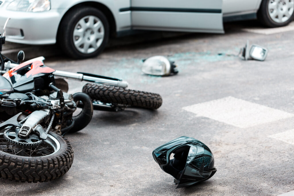 Overturned motorcycle and helmet on the street after collision with a car